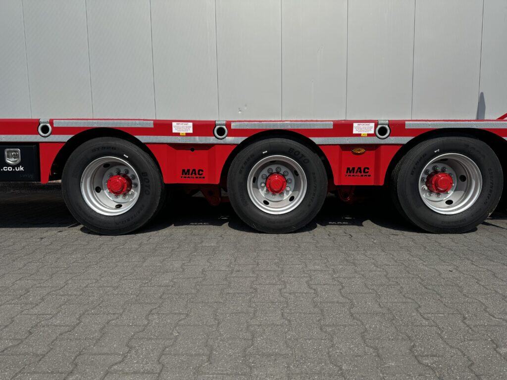 Robuuste rode oplegger met fourwielige banden, geschikt voor zwaar transport en logistiek.