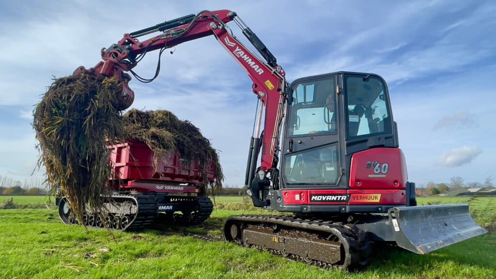 Gebruik van een compacte graafmachine voor het opruimen en verwijderen van natuurresten op het land.