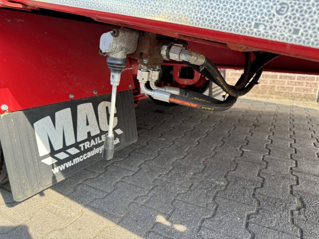 Robuuste hydraulische koppelingen onder een trailersysteem voor optimale verbinding en veiligheid.