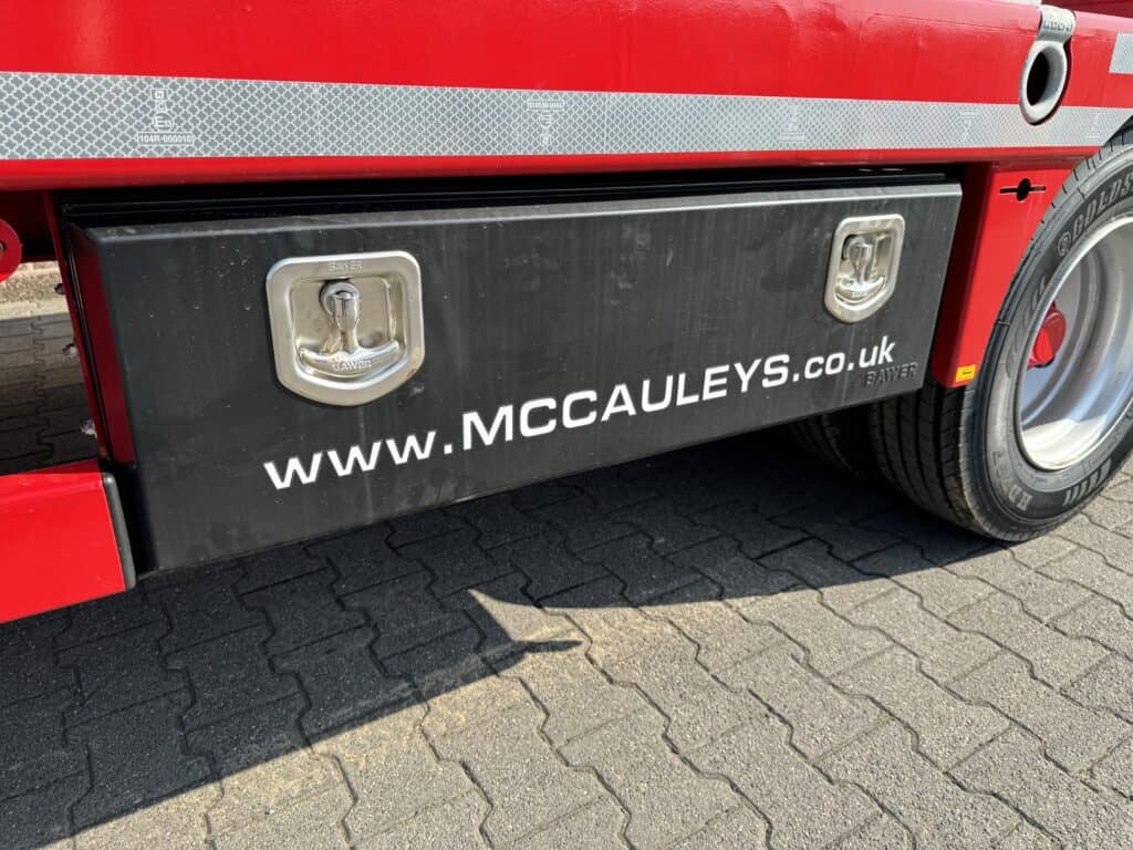 Alt tekst: Vrachtwagen opslagbak met website link www.mccauleys.co.uk op zwarte zijpanelen.