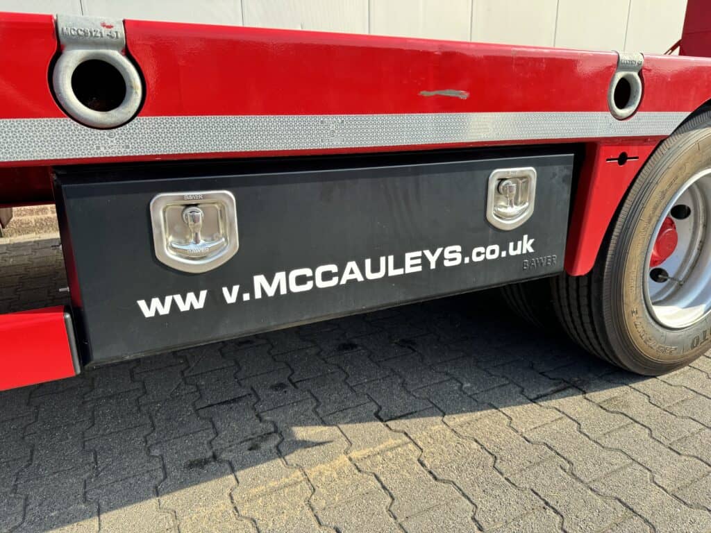 Modulaire vrachtwagen met opvallende rode kleuren en website URL mcauleys.co.uk.