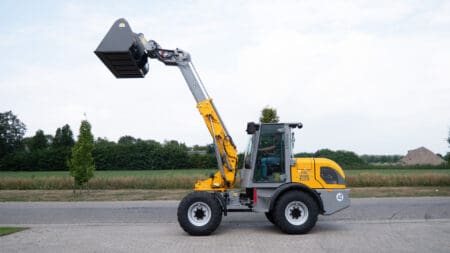 Hoogwerkermachine met hefarm voor bouw- en landwerk, geel en zwart, op straat.