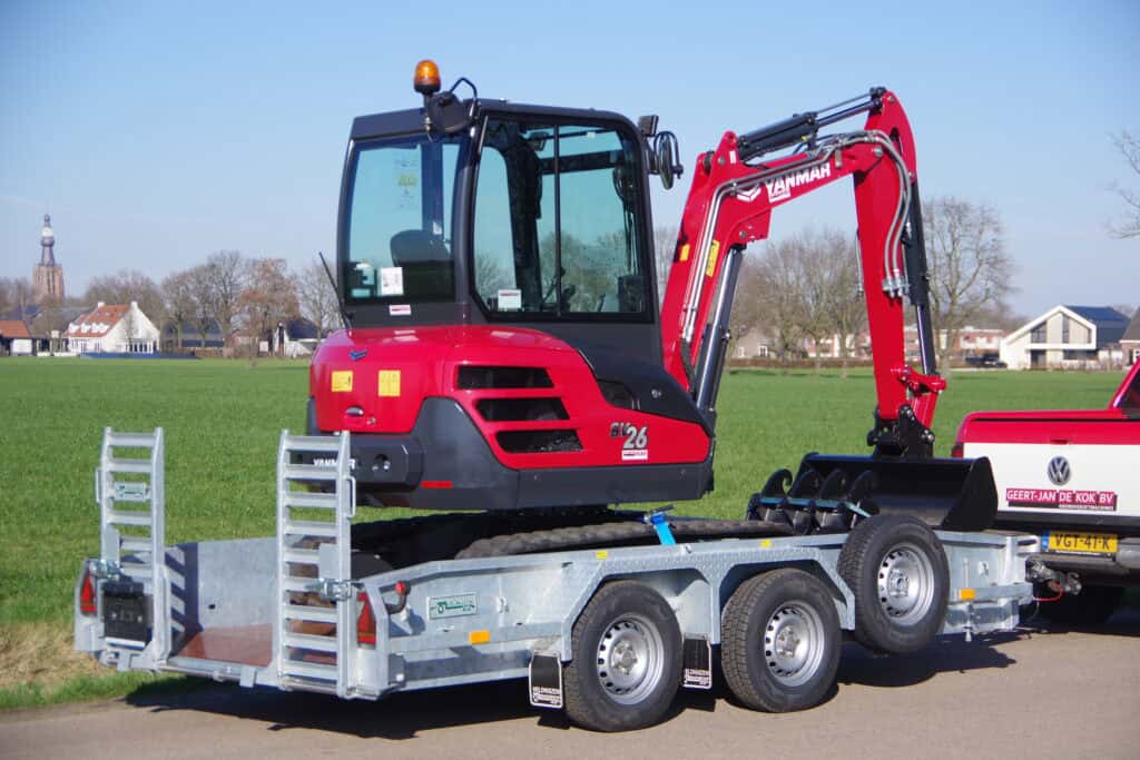 Veegmachine op aanhangwagen met mini graafmachine voor tuin- en landschapsinrichting.