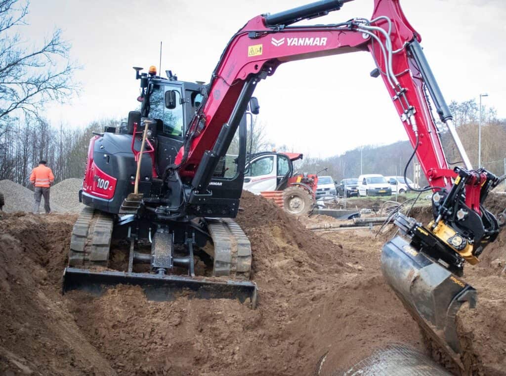 Zwarte en rode graafmachine op een bouwplaats, gespecialiseerd in grondwerk en infra.