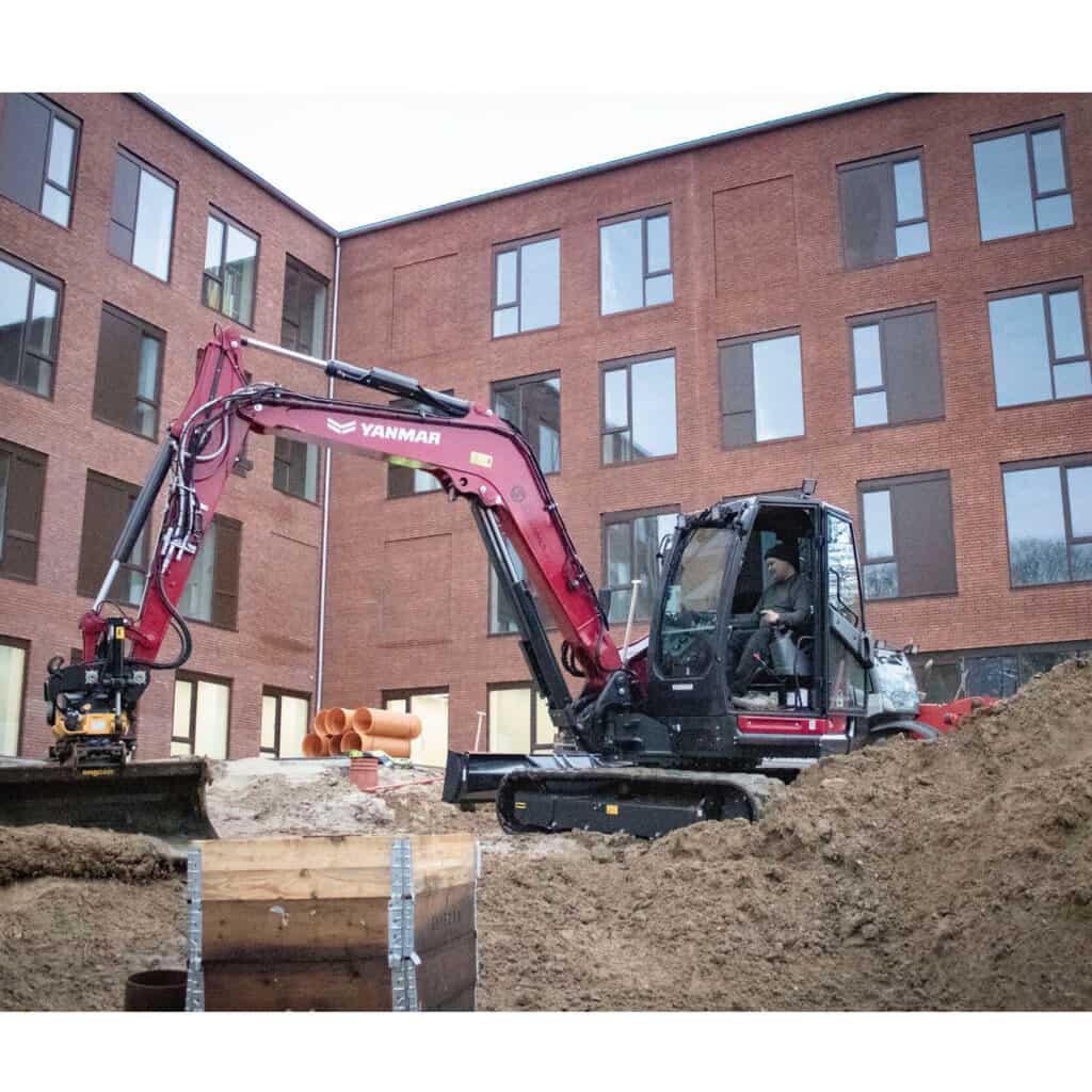 Zwenkgraver op een bouwplaats voor grond- en funderingswerkzaamheden in een stadsomgeving.