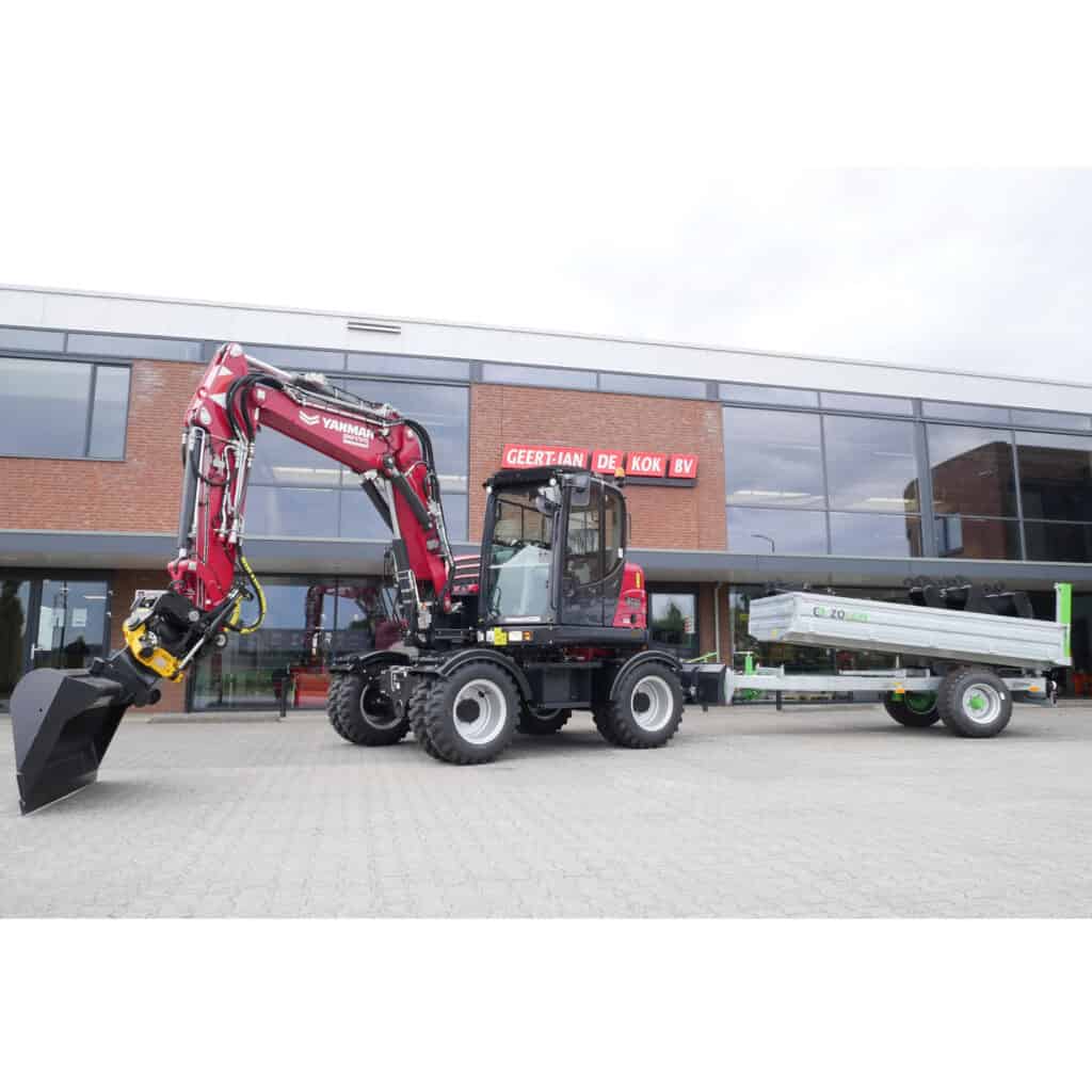 Compacte graafmachine met bak en aanhanger voor bouw- en infrastructuurwerkzaamheden.