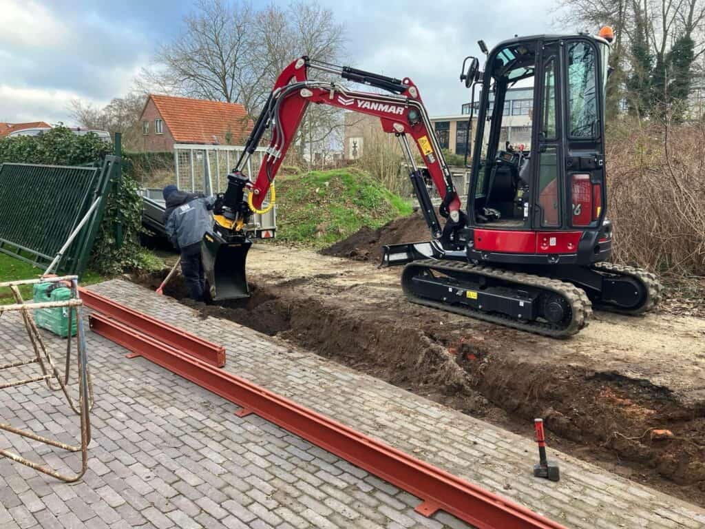 Miniatuur van een minikraan die ondergrondse werkzaamheden uitvoert op een bouwplaats.