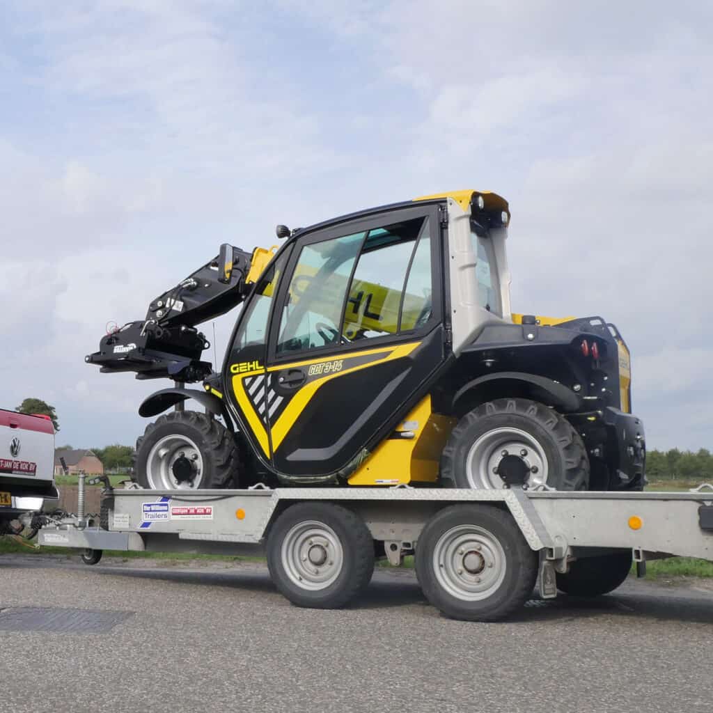 1. Zwarte en gele Gehl compact tractor op transportwagen.