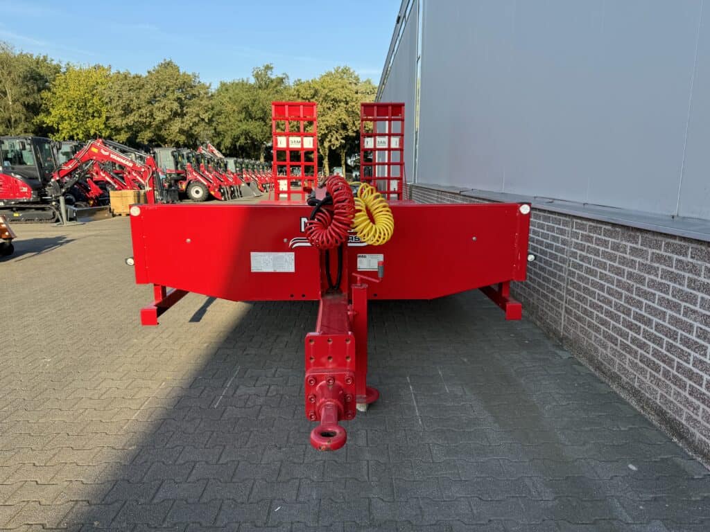 Robuuste rood gekleurde aanhangwagen voor bouw- en tuinwerkzaamheden met hydraulische functies.