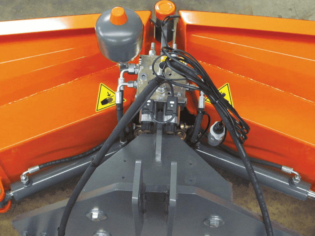 Uitzicht op agrarische montage met hydraulische aandrijving en veiligheidswaarschuwingstekens.