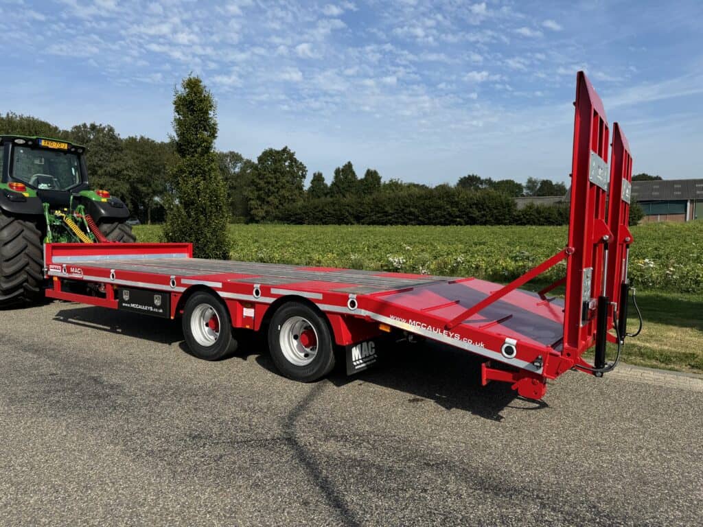 Veetransportwagen met flatbed en oprijgoot voor landbouw- en bouwmaterialen, getrokken door een tractor.
