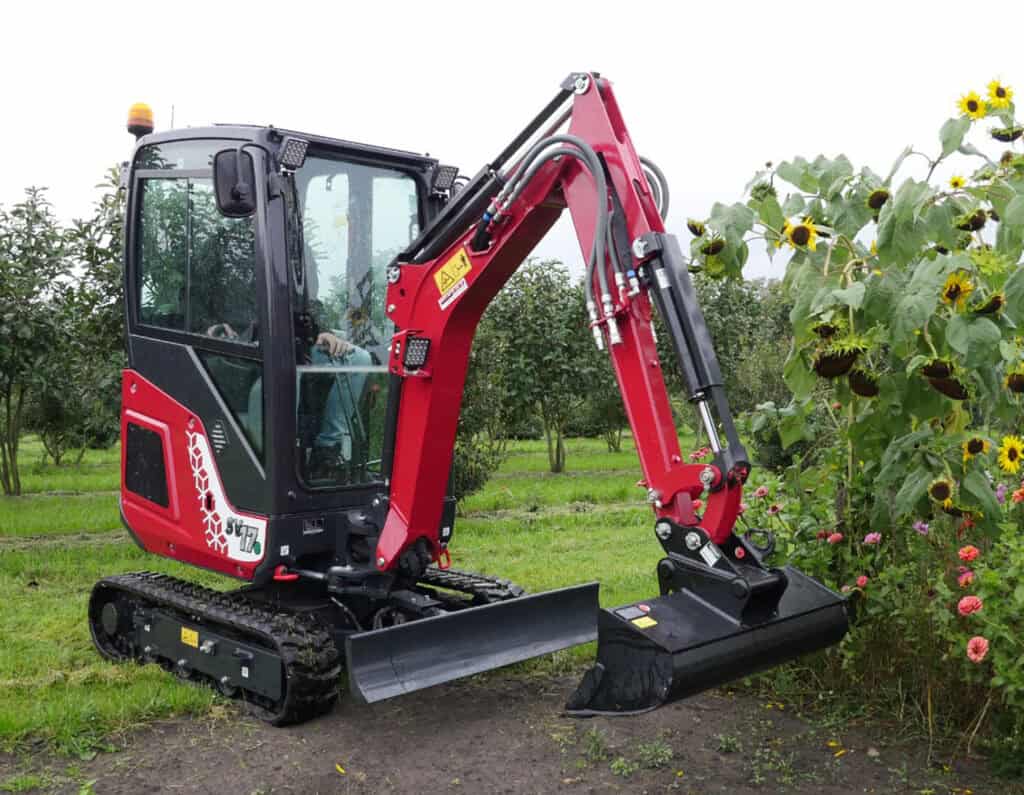 Klein minigraver bij werkzaamheden op een tuin, geschikt voor tuinieren en landschapsarchitectuur.