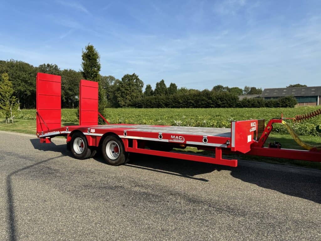 Veelzijdige rode autotransporter trailer voor het vervoer van voertuigen en machines.
