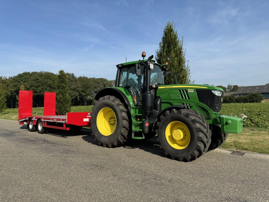 Efficiënte landbouwtractor met rood aanhangwagen voor tuinbouw en agrarisch gebruik.