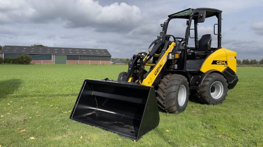 Kleurenrijk Gehl skidder met frontlader op groen veld, voor landbouw en bosbouw toepassingen.