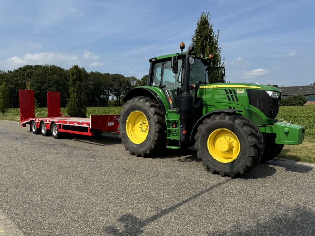 Motor getrokken landbouwwagen met groene tractor en grote banden, geschikt voor landbouwwerkzaamheden.