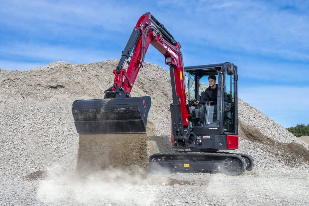 1. Mini-graver op bouwplaats met Yanmar-motor onder een heldere blauwe hemel.