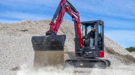 1. Mini-graver op bouwplaats met Yanmar-motor onder een heldere blauwe hemel.