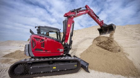 Klein bouwmachine graaft zand op een bouwplaats.