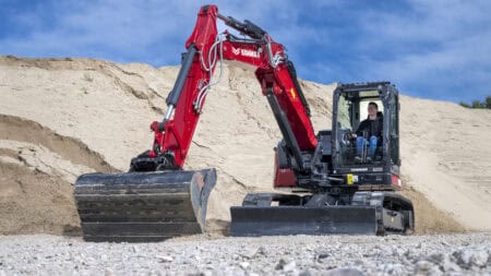 - Compacte Yanmar graafmachine op een bouwplaats in de natuur.