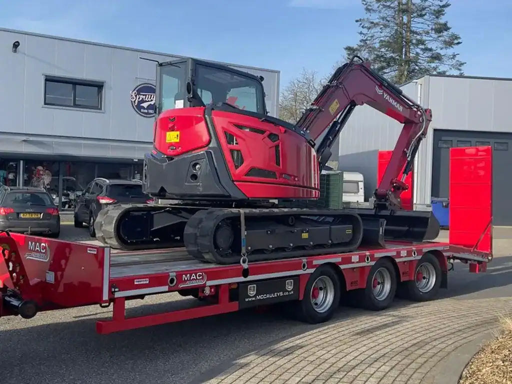 Compacte graafmachine op transportwagen voor bouw- en groenprojecten.