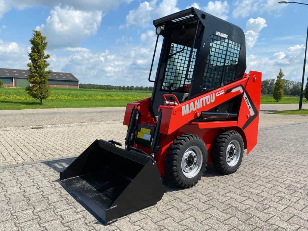 Kompakt skidlaadmachine op een verharde ondergrond, ideaal voor bouw en tuinieren.