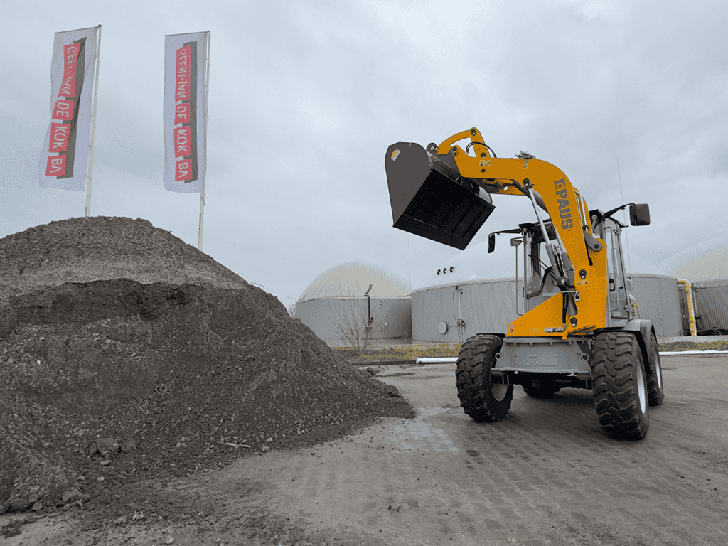 Zandbak met bouwpakket en heftruck van Geert-Jan de Kok B.V., gespecialiseerd in bouwmaterialen en mini-heftrucks.