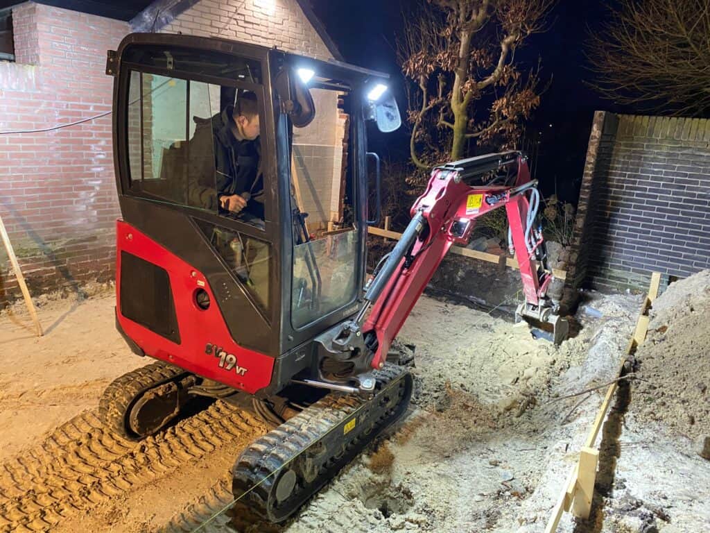 Mini graafmachine bij woningbouwproject op locatie.