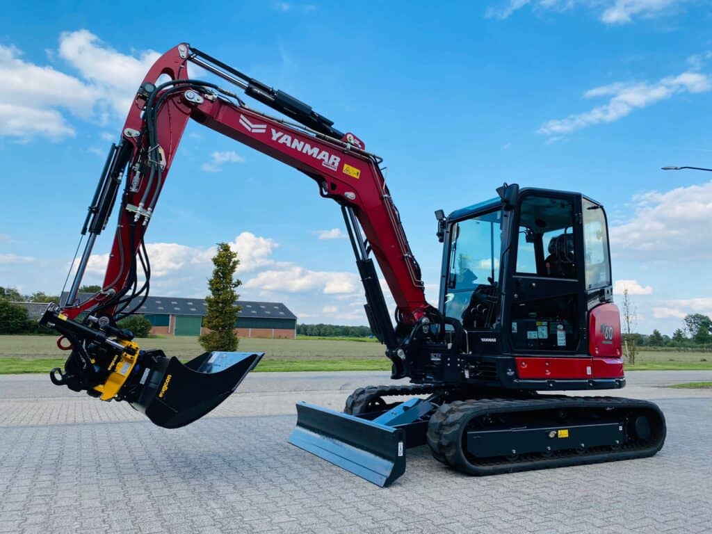 Kleine graafmachine van Yanmar met cabine op een parkeerplaats onder een blauwe hemel.