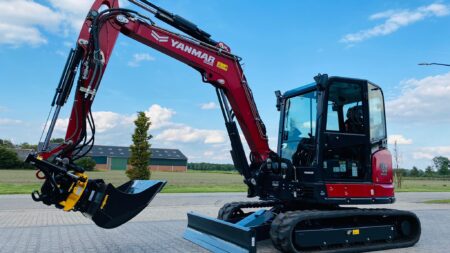 Kleine graafmachine van Yanmar met cabine op een parkeerplaats onder een blauwe hemel.