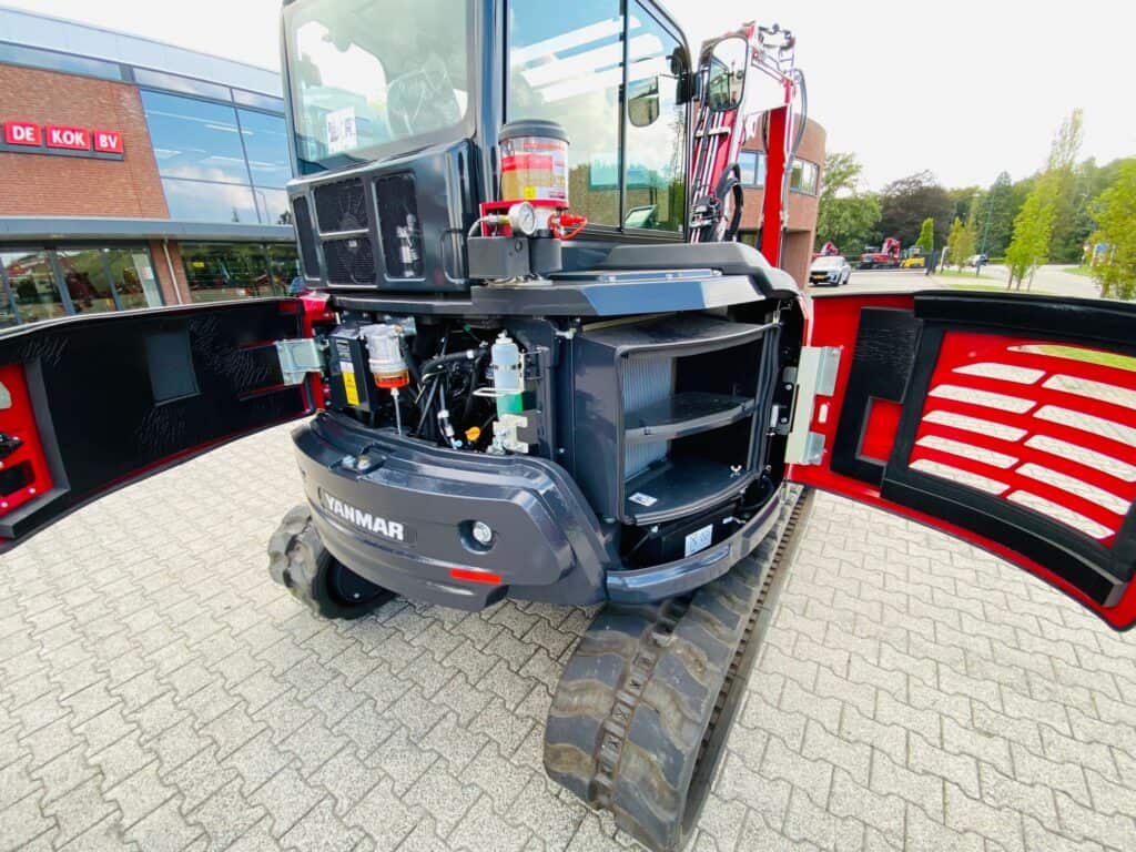 Compacte minigraafmachine met open motorkap, geschikt voor tuin- en bouwprojecten.
