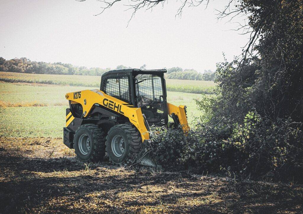 Hoge kwaliteit mini skid steer loader van GEHL in een landelijke groen omgeving.