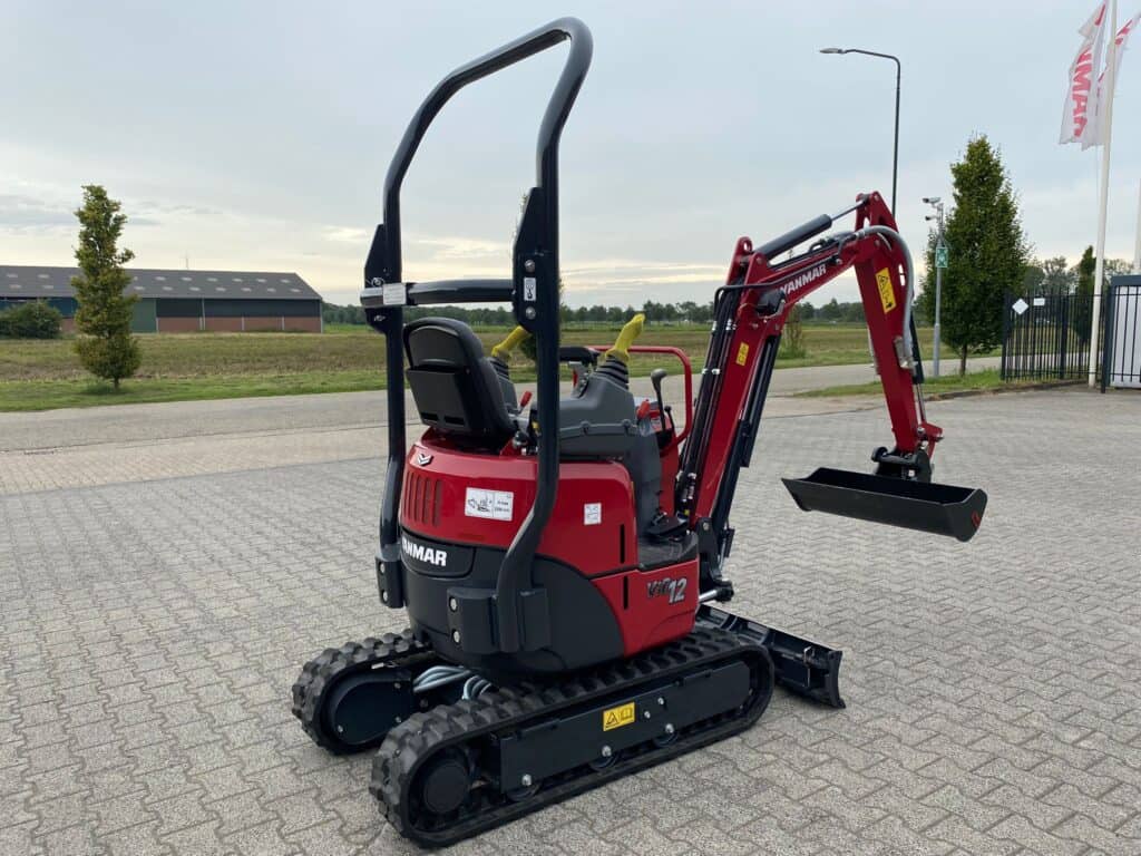 Klein minigraver op verharde ondergrond, gealigneerd in open veld.