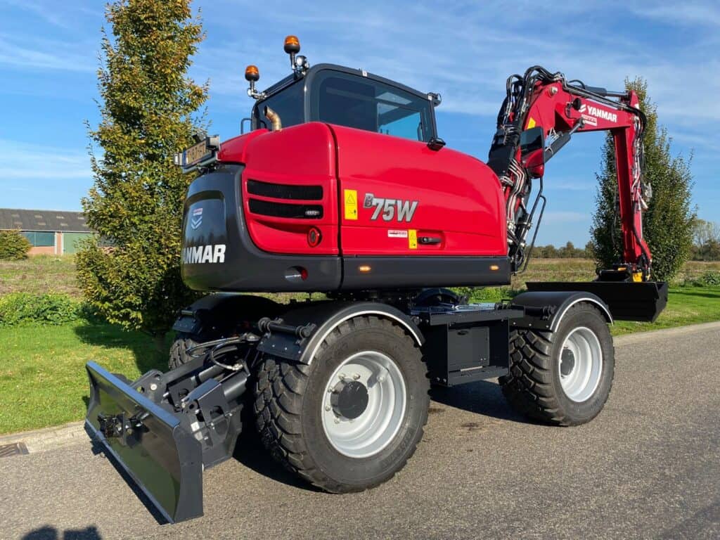 Kleine compacte wiellader met hijsarm en cabine, geschikt voor landbouw en tuinbouw.