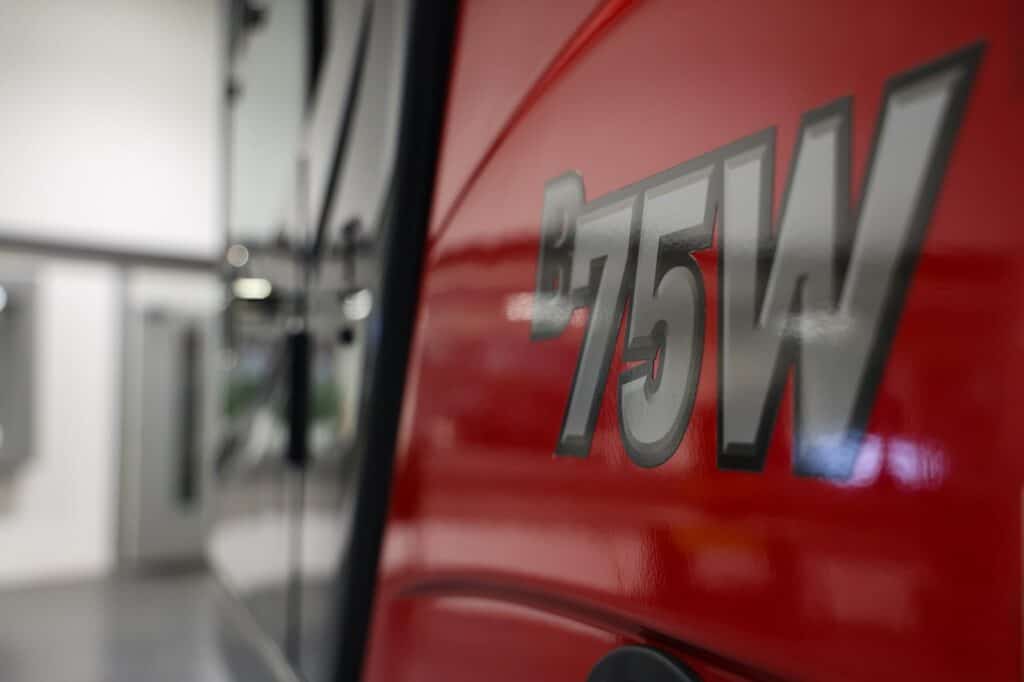 Veiligheidslicht op brandweerauto, met focus op het rode verfwerk en het logo.