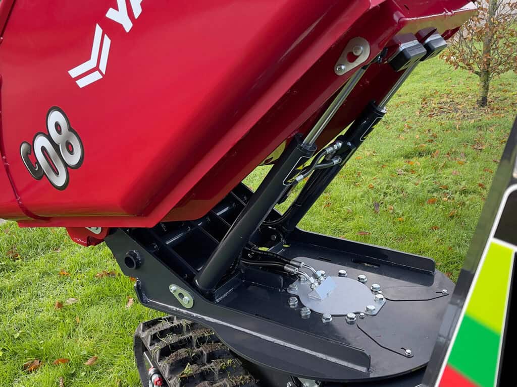 Robuuste mini kraan met hydraulische functies op een grasveld.