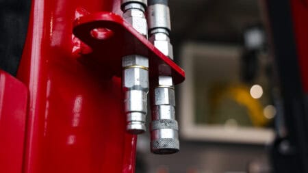 Stalen hydraulische slangen en koppelingen op een machine of voertuig.