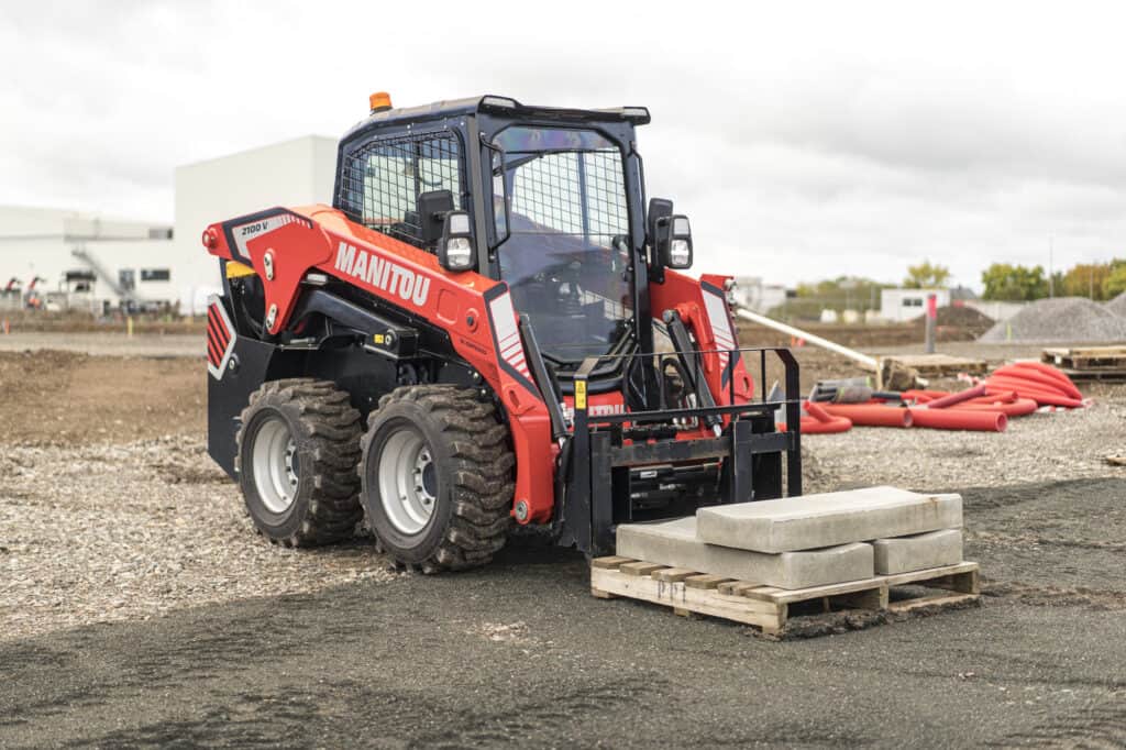 Manitou laadbak met pallet en betonstenen op bouwplaats, professioneel hijsmiddel voor bouwmaterialen.