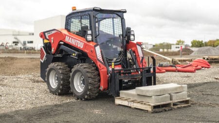 Manitou laadbak met pallet en betonstenen op bouwplaats, professioneel hijsmiddel voor bouwmaterialen.