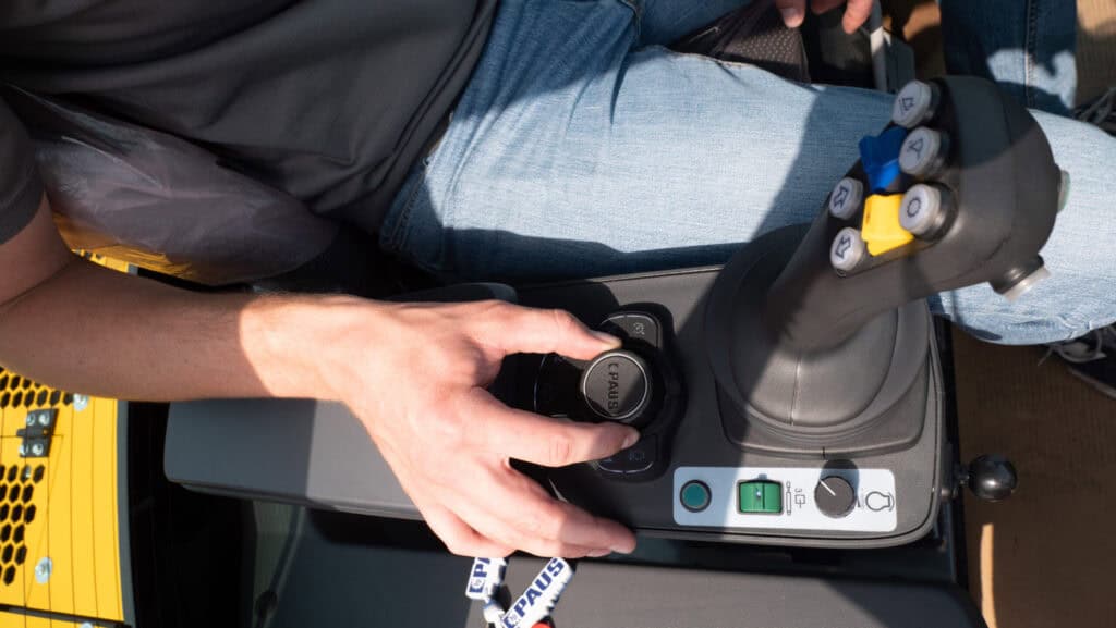 Flexibele graafmachine bediening met joystick en bedieningsknoppen op bouwmachine.