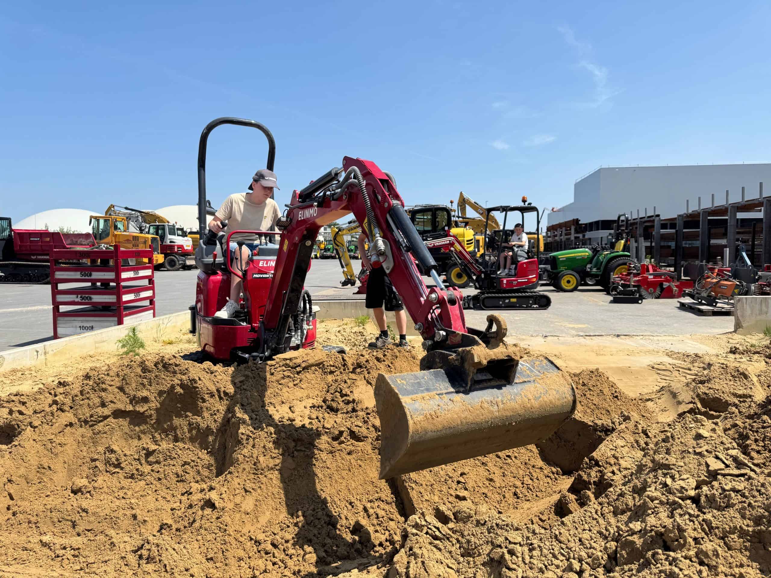 Mini shovel machine werkzaamheden bouwplaats, jonge jongen werkt met mini graafmachine.