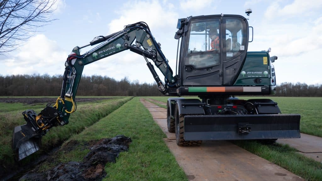 Zeer gedetailleerde mini graafmachine op een grasveld, ideaal voor landbouw en tuinbouw.
