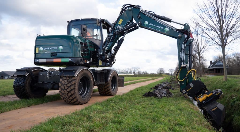 Robuuste minigraver met groene bedrijfskleuren van Jos Kanters voor grond- en wegreparatie.