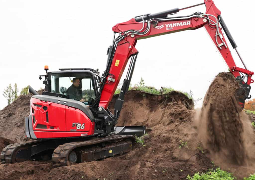Kleine graafmachine in actie bij grondwerkzaamheden op bouwterrein.
