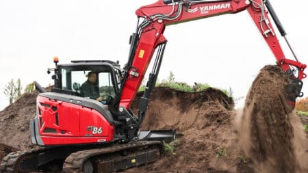Kleine graafmachine in actie bij grondwerkzaamheden op bouwterrein.