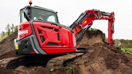 Zeer leesbare mini excavator op bouwplaats met werkzaamheden voor riolering en fundering.