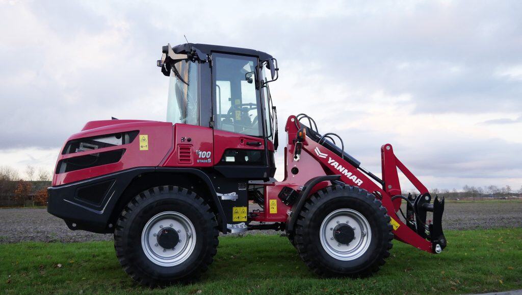 Stalled tractor met frontlader op een grasveld, landbouwmachine in Nederland.