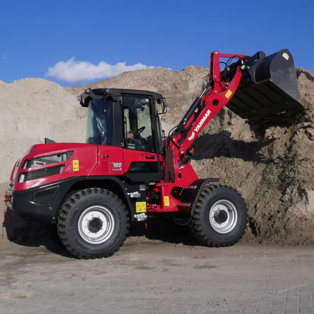 Kleine foto van een rode wiellader bij een bouwplaats, geschikt voor grondverzet en bouwprojecten.