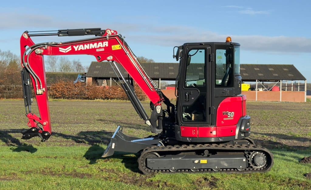 Yanmar mini graafmachine op een groene werkplaats, ideaal voor grondwerk en tuinprojecten.